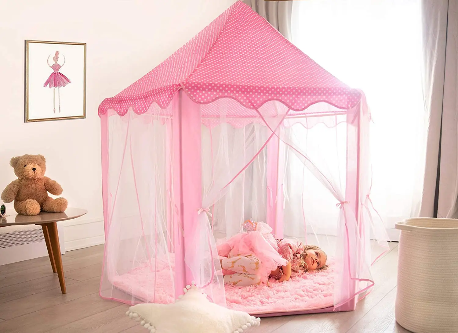 Carpa castillo hexagonal rosa de poliéster para niñas, con cortinas de tul blanco y techo punteado, montada sobre alfombra peluda en habitación infantil.