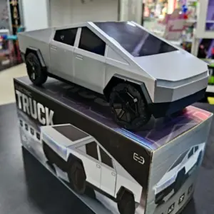 Carro de control remoto Cyber Truck gris plateado con diseño futurista angular, sobre su caja de empaque con ilustraciones del modelo.