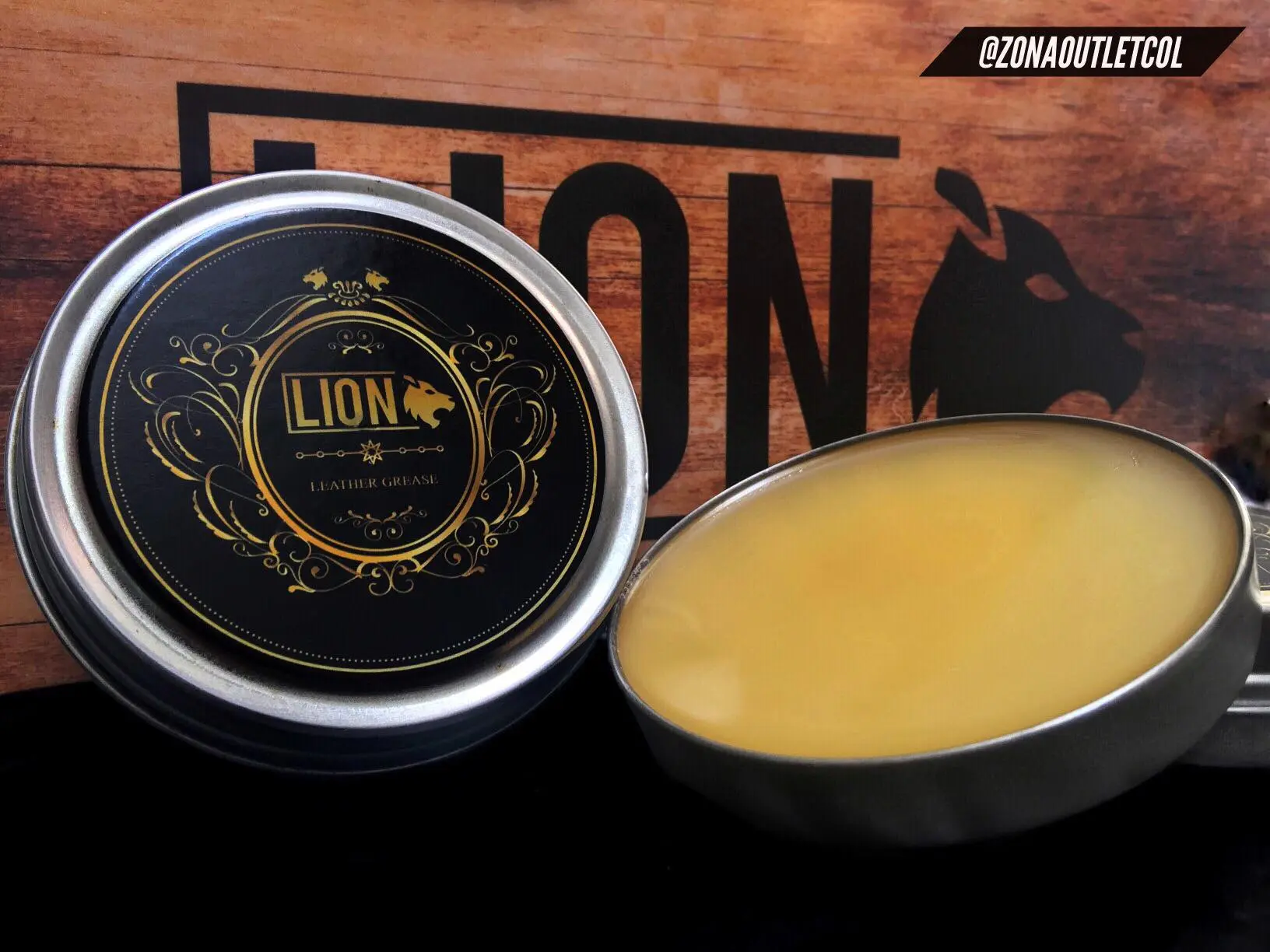 Set de dos latas de grasa nutritiva redondas con tapa plateada y contenido de cera amarilla clara para mantenimiento de cuero y botas sobre fondo de madera