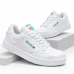 Zapatillas Reebok Club blancas de corte bajo con detalles verdes y rojos, mostradas en ángulo sobre pedestales blancos.