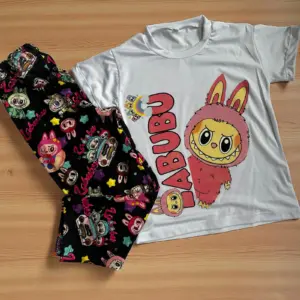 Pijama de dos piezas con camiseta blanca de manga corta con diseño de Labubu y leggings negros con estampado multicolor de personajes y estrellas.