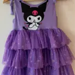 Vestido infantil lila con diseño de Kuromi, tirantes ajustables y falda escalonada de tul con brillo y estrellas doradas.