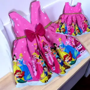 Dos vestidos de fiesta infantiles fucsias con estampado de princesas y castillos, decorados con lazo y ribete dorado brillante.