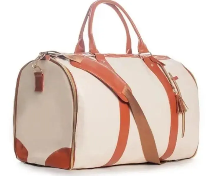 Bolso de viaje beis con detalles en cuero caramelo, asas superiores, correa cruzada y cremalleras doradas.