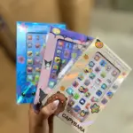 Mano sosteniendo tres cajas holográficas de celulares didácticos infantiles con diseños de Stitch, Kuromi y Capybara para aprendizaje temprano.