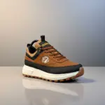 Zapatos casuales Brahma de material sintético marrón con detalles negros y suela gruesa de PVC blanca en estudio.
