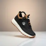 Zapatilla casual Brahma negra y marrón en material sintético con suela blanca y pisada de goma, ángulo lateral en superficie blanca.
