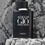 Frasco negro mate de perfume Acqua di Gio Profumo de Giorgio Armani con detalles plateados sobre un fondo de rocas grises texturizadas.