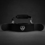 Arm Blaster negro para bíceps con soporte rígido, correas acolchadas y logo de oso blanco, vista frontal sobre fondo oscuro.