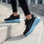 Zapatillas Asics negras con suela alta de espuma celeste con motas, usadas para caminar y correr en escaleras urbanas.