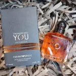 Perfume Emporio Armani Stronger With You Intensely 100 ml y su caja gris con detalles cobrizos sobre papel triturado.