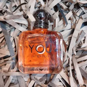 Perfume Emporio Armani Stronger With You Intensely en frasco cuadrado de vidrio ámbar sobre cama de papel picado reciclado.