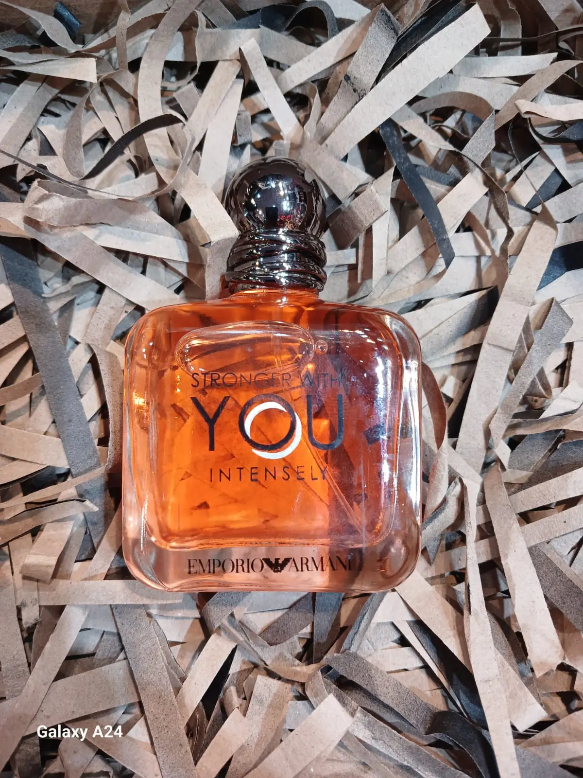 Perfume Emporio Armani Stronger With You Intensely en frasco cuadrado de vidrio ámbar sobre cama de papel picado reciclado.