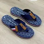 Sandalias Tommy Hilfiger para dama, diseño thong en azul marino con monograma blanco, correa de tela azul, detalle marrón y suela tricolor.