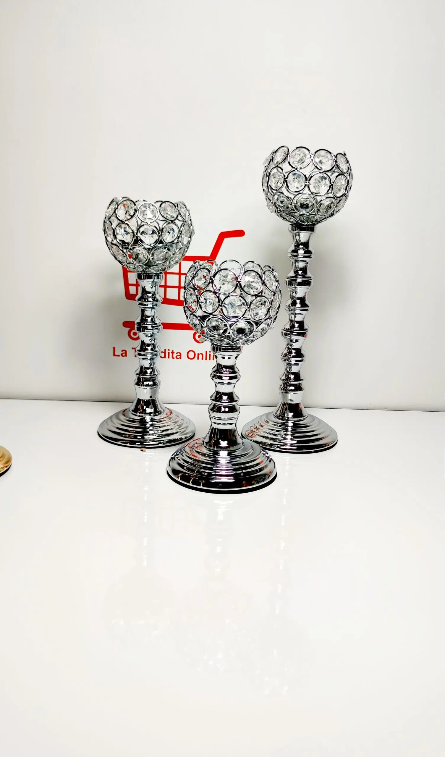 Set x3 candelabros de pedestal en metal plateado y esferas de cristal facetado con diferentes alturas sobre superficie blanca.