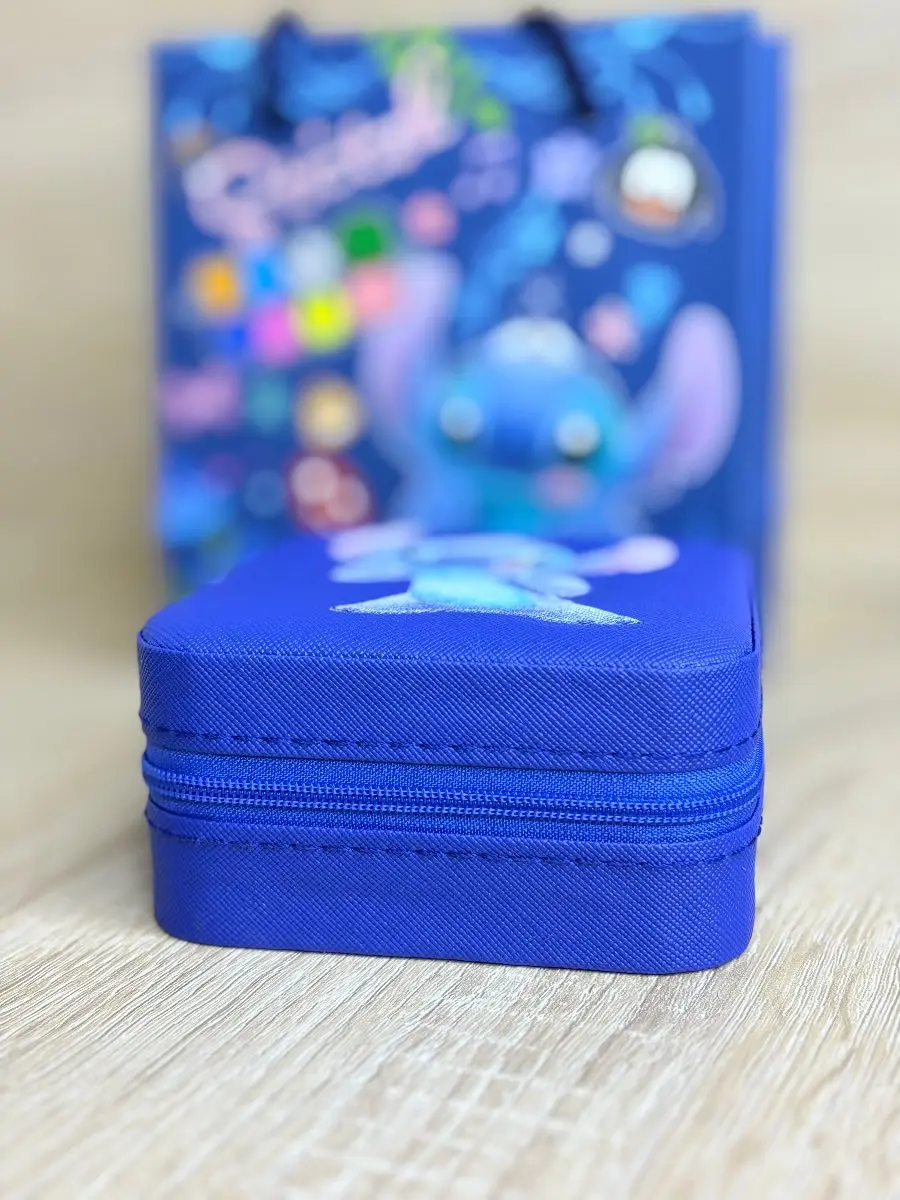 Estuche rígido azul cuadrado con de Stitch sobre superficie de madera y bolsa de regalo temática al fondo