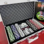 Maletín metálico plateado abierto con interior de espuma, 300 fichas apiladas en varios colores, barajas de naipes y dados.