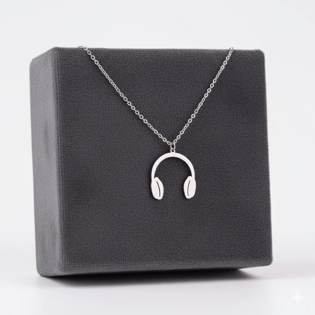 Collar de acero inoxidable plateado con dije de audífonos, presentado sobre una caja de exhibición gris oscuro.