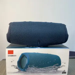 Parlante portátil Bluetooth azul marino con rejilla textil colocado sobre su caja original que muestra el modelo Charge 5 y protección contra agua.