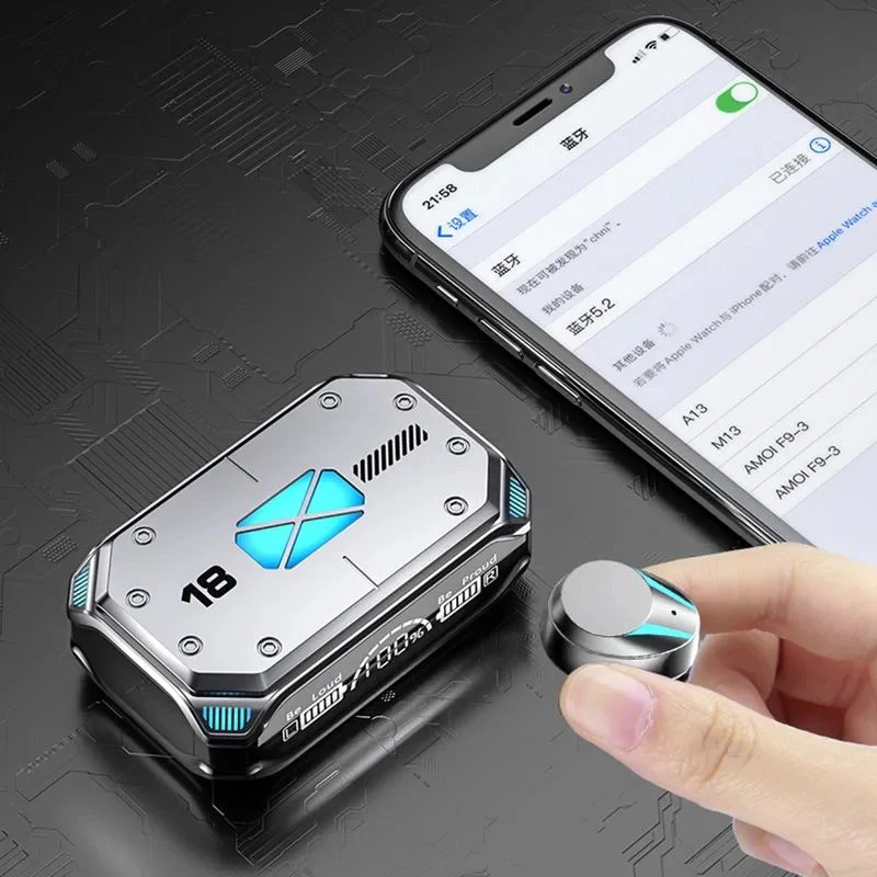 Audífonos gamer inalámbricos Bluetooth grises estilo futurista junto a su estuche de carga digital y un celular mostrando la conexión