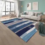 Tapete con franjas abstractas en azul marino, celeste y gris sobre piso de madera en una sala moderna con sofá blanco.