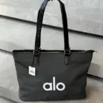 Bolso tote negro Alo de gran capacidad con textura acanalada, asas de cuero sintético y logotipo blanco frontal.