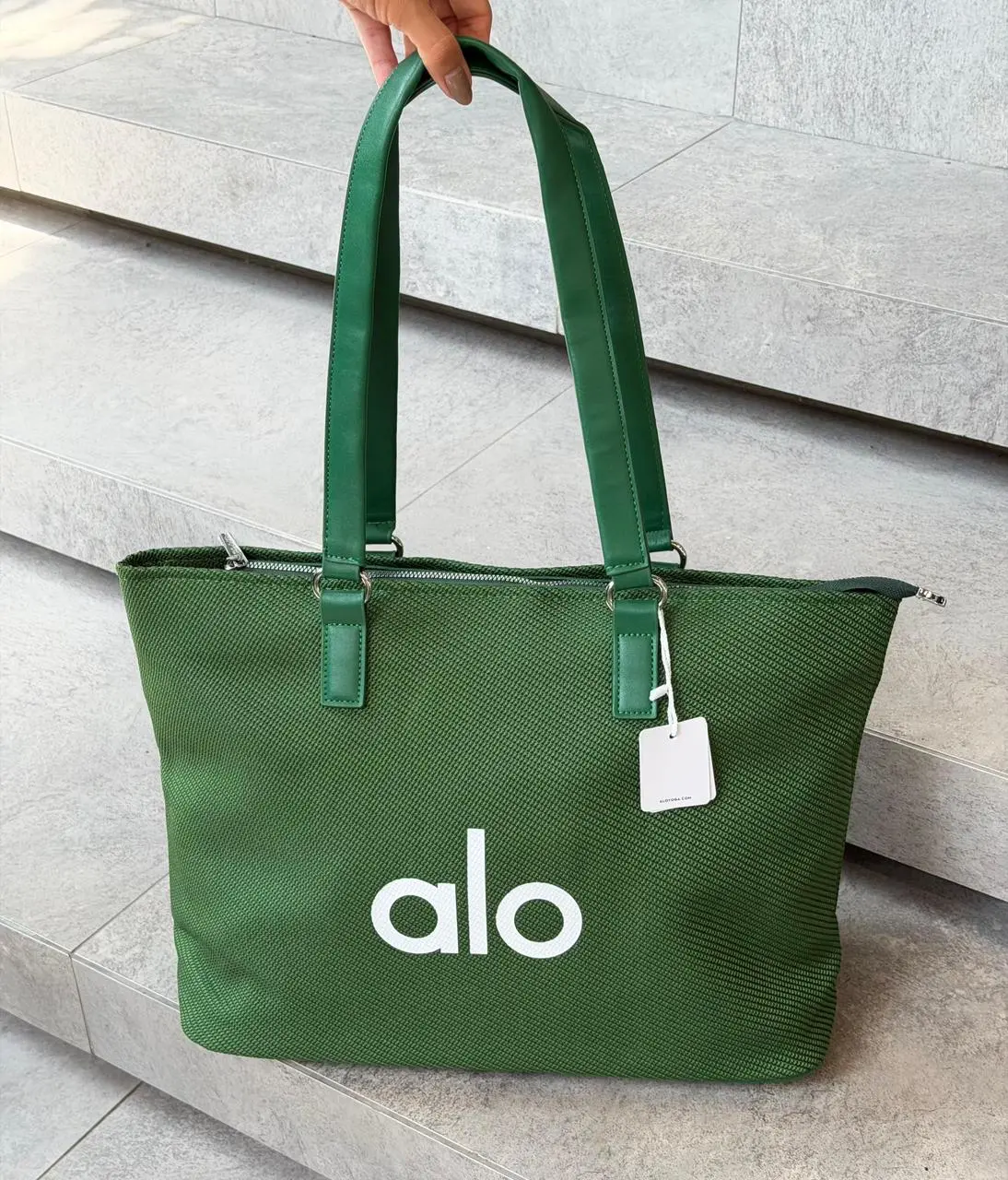 Bolso tote verde oscuro de gran capacidad con asas de cuero sintético, textura acanalada y logotipo blanco alo en la parte frontal.