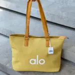 Bolso tote amarillo Alo grande de gran capacidad con textura tejida, asas de cuero sintético y cierre de cremallera superior.