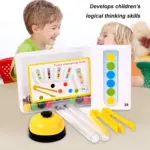 Dos niños sonrientes junto a un set Montessori de tubos de plástico transparente, pinzas amarillas, tarjetas con patrones y bolas coloridas sobre una mesa.