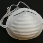 Tapabocas industrial desechable blanco moldeado con pliegues horizontales, pinza nasal metálica y bandas elásticas.