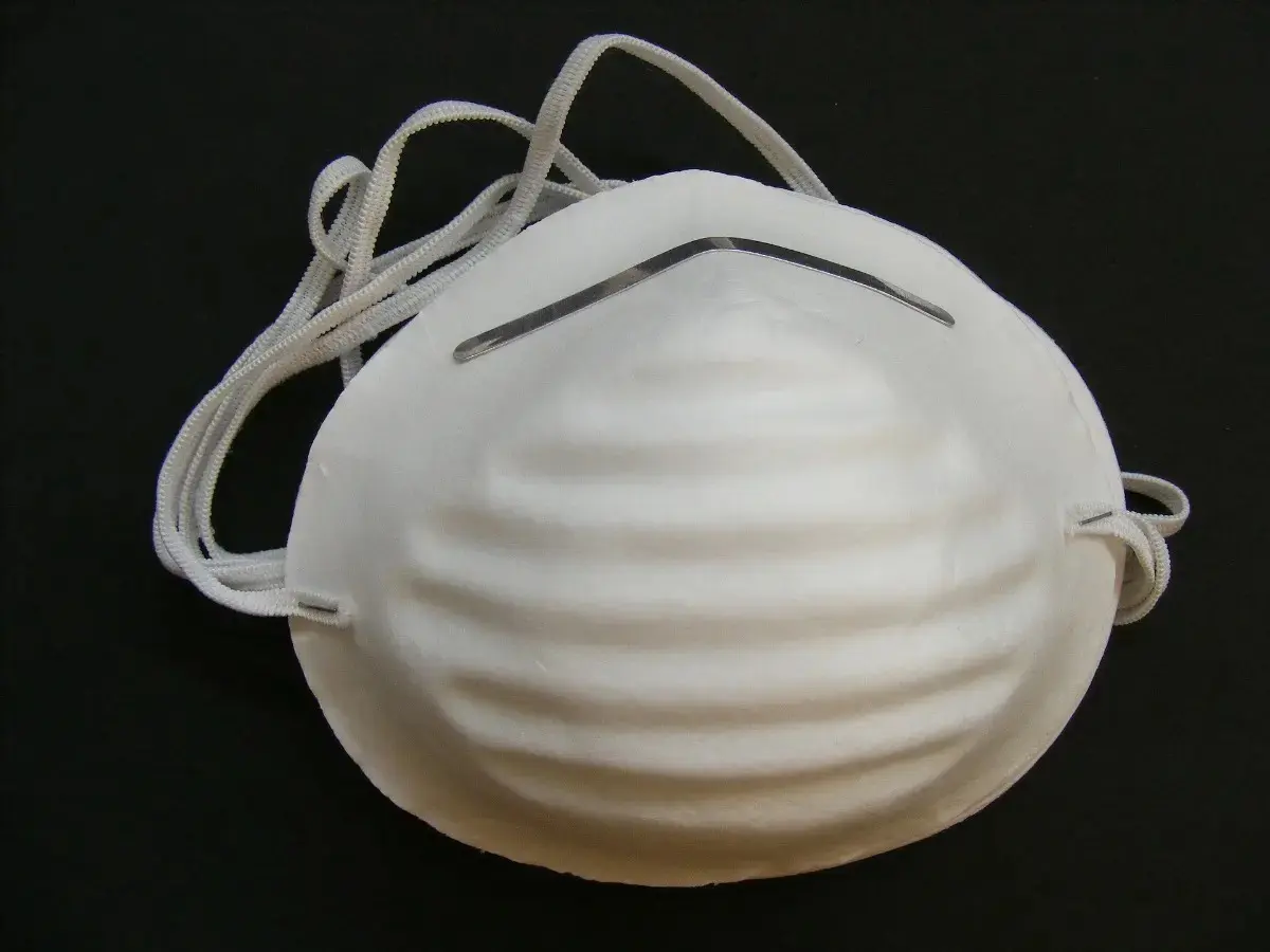 Tapabocas industrial desechable blanco moldeado con pliegues horizontales, pinza nasal metálica y bandas elásticas.