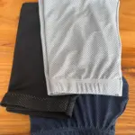 Pila de tres bóxers deportivos de tela licrada microperforada en colores gris, negro y azul oscuro sobre una mesa de madera.