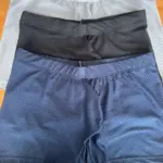 Tres bóxers transpirables de tela licrada con diseño microperforado en colores gris, negro y azul marino, apilados verticalmente sobre superficie de madera.
