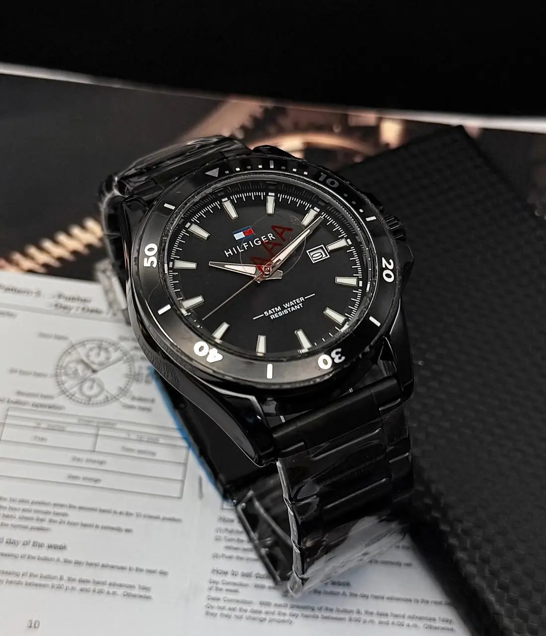Reloj Tommy analógico negro para caballero en acero con fechador y bisel giratorio sobre caja.
