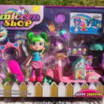 Set de juguete Unicorn Shop con muñeca de cabello verde, scooter rosa con puesto de postres, accesorios de unicornio y mini dulces en caja.