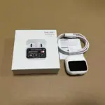 Audífonos inalámbricos A11 blancos con estuche de carga con pantalla táctil, cable y manual junto a su caja sobre fondo café.