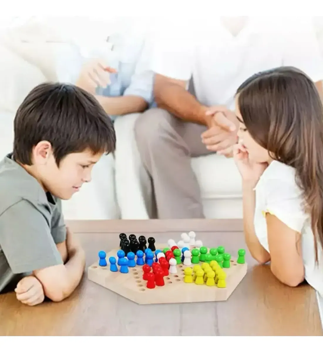 Juego de damas chinas de madera con tablero hexagonal y fichas de colores en base de madera, mientras dos niños juegan sentados alrededor de una mesa.