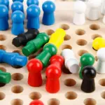Juego de damas chinas de madera con tablero perforado y fichas cilíndricas coloridas dispuestas en la superficie.