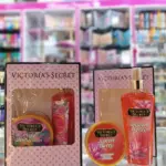 Kits de Victoria's Secret con crema y splash, uno en caja rosa y otro de la línea Juiced Berry con envases color naranja y diseño floral.