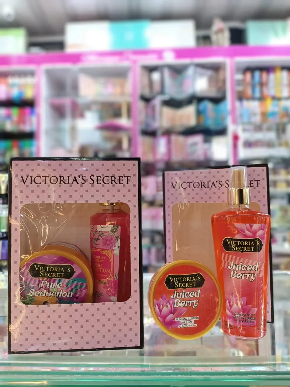 Kits de Victoria's Secret con crema y splash, uno en caja rosa y otro de la línea Juiced Berry con envases color naranja y diseño floral.