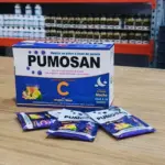 Caja azul de 24 sobres y tres sobres sueltos de bebida en polvo para la noche con jengibre y menta sobre superficie de madera.