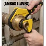 Dos llaves de correa amarillas con banda de goma negra sujetando una pieza de bronce en una tubería para plomería sin rayar superficies.