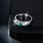 Anillo de moisanita verde en plata 925 con diseño lateral brillante sobre superficie negra.