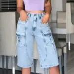 Bermuda cargo denim de tiro alto en azul claro lavado, con bolsillos laterales y estilo Y2K, vista frontal de cuerpo completo.