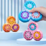 Juguetes antiestrés triangulares con cuentas de colores giratorias en tonos azul, naranja y rosa sobre pedestales celestes.