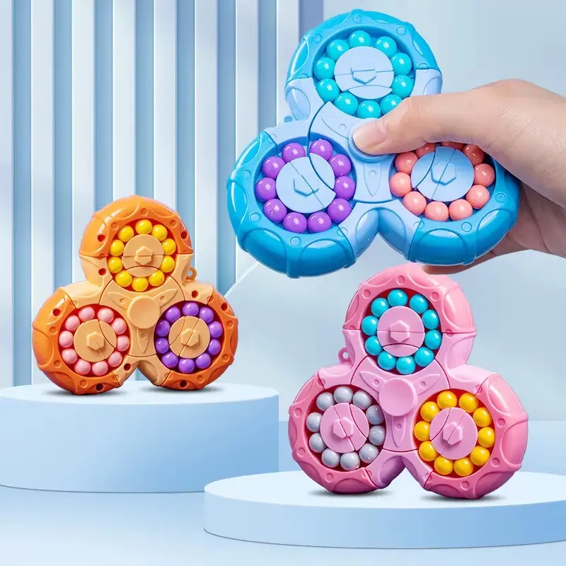 Juguetes antiestrés triangulares con cuentas de colores giratorias en tonos azul, naranja y rosa sobre pedestales celestes.