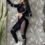 Conjunto deportivo negro de manga larga con recortes de malla transparente, líneas blancas de diseño y ajuste ceñido.