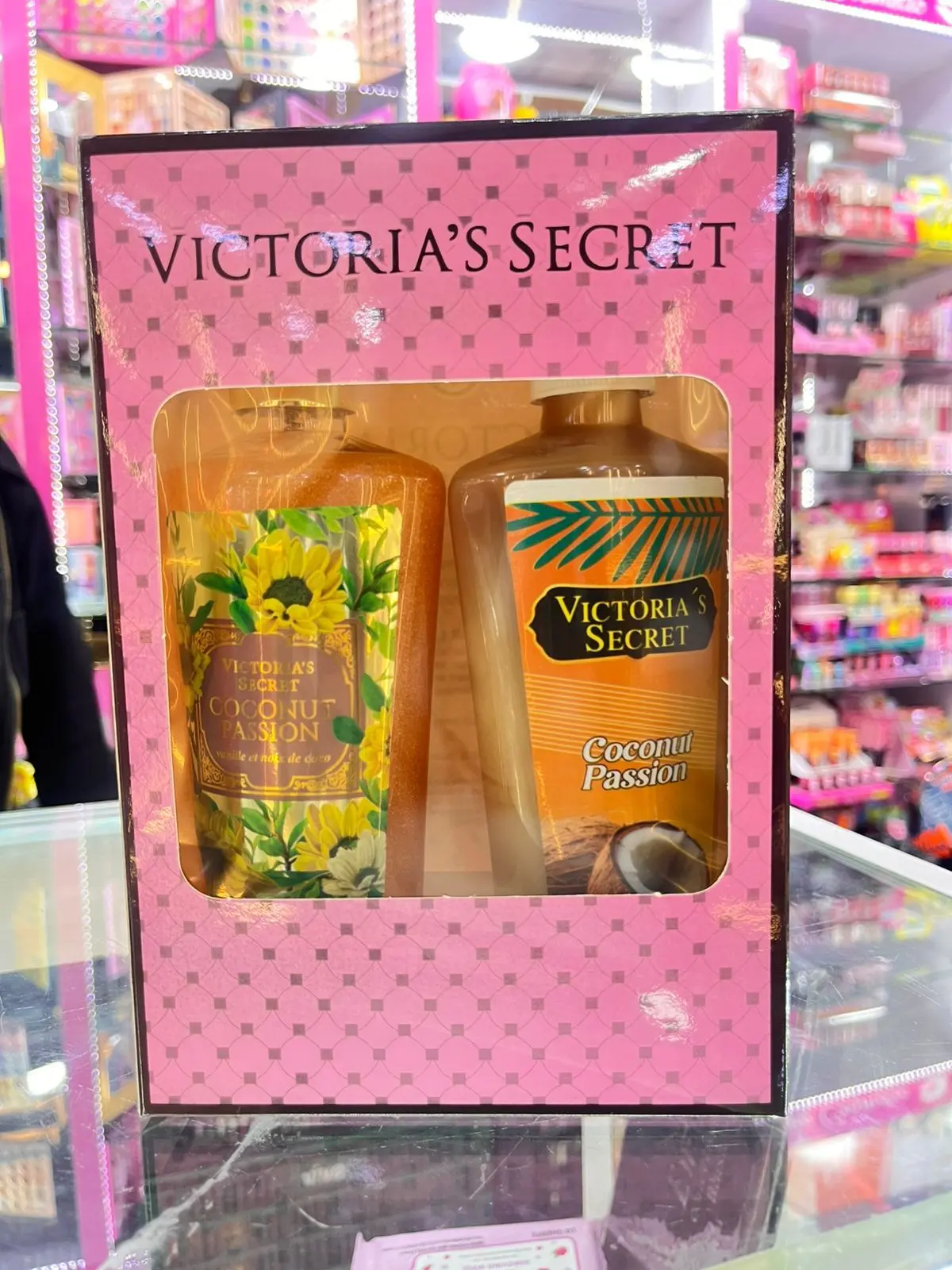 Set Victoria's Secret Coconut Passion en caja rosa con ventana, incluye crema y splash con motivos de coco y flores amarillas.