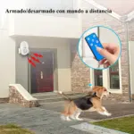Detector de movimiento inalámbrico blanco con control remoto azul, instalado en la entrada exterior de una casa junto a una puerta de madera.