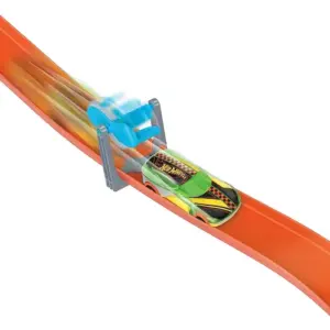 Carro de juguete verde y amarillo Hot Wheels pasando rápidamente bajo un aro azul giratorio en una pista naranja.